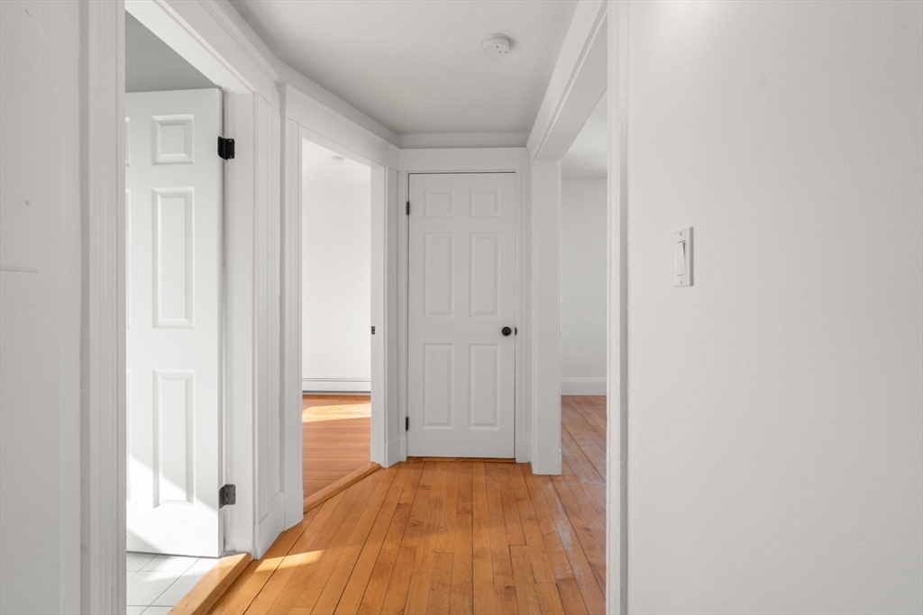 215 Ash Street, Unit 3 Waltham, MA 02453 - Photo 8 of 18 a view of a bedroom with wooden floor and a bathroom