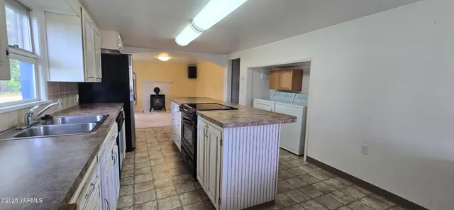 a kitchen with granite countertop a sink a stove top oven a granite counter space and cabinets