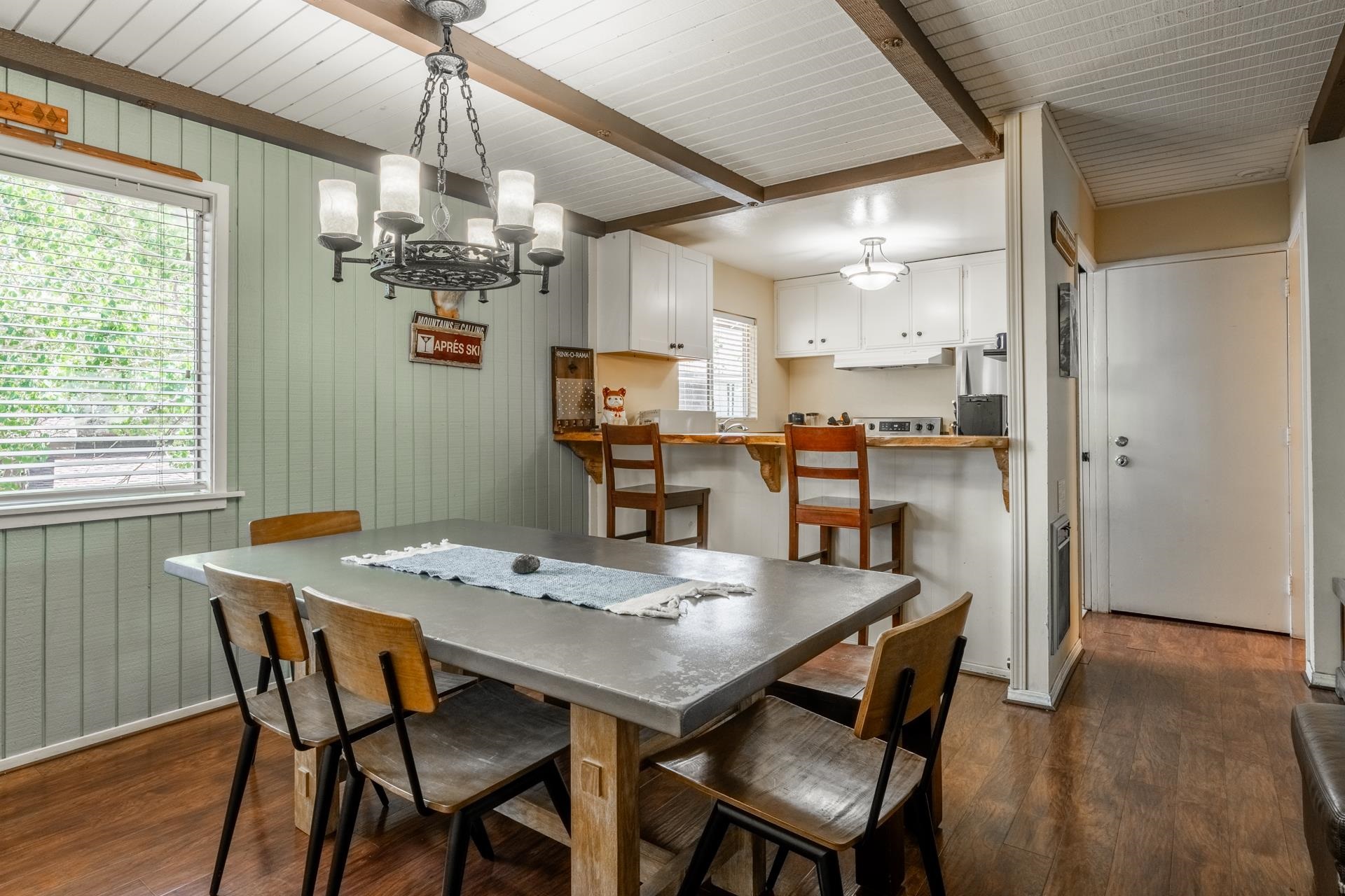 165 Old Mammoth Road, Unit 3 Mammoth Lakes, CA 93546 - Photo 10 of 48 Dining area featuring a decorative chandelier, vertical plank wall paneling, and wood-finish flooring