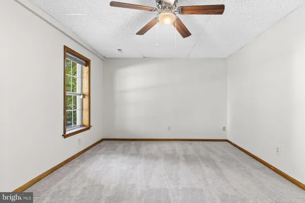 an empty room with a window and a ceiling fan