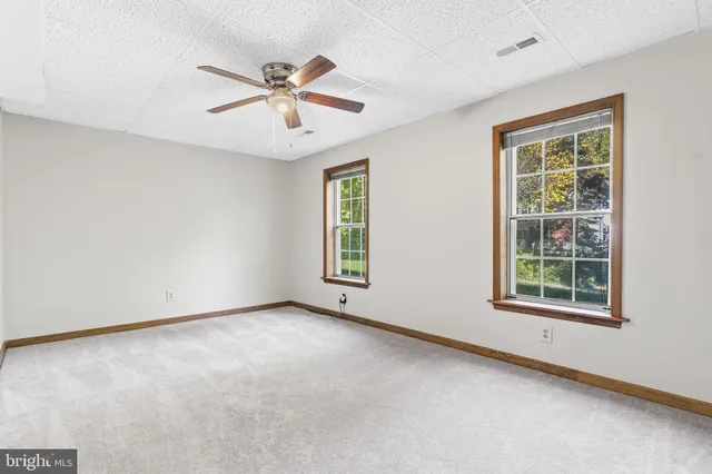 an empty room with windows and fan