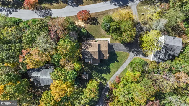 an aerial view of residential house with outdoor space and trees all around