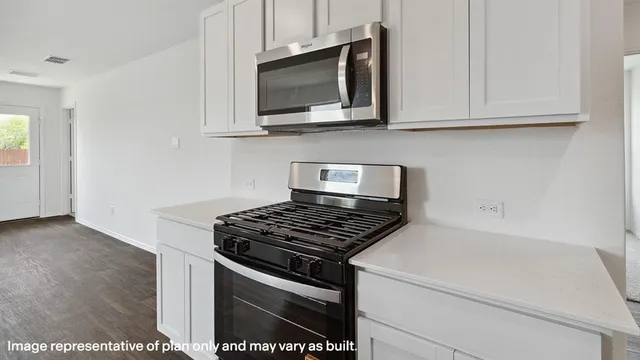 a kitchen with stainless steel appliances granite countertop white cabinets and a stove top oven