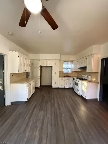 a kitchen with stainless steel appliances kitchen island wooden floors granite counter tops and white cabinets