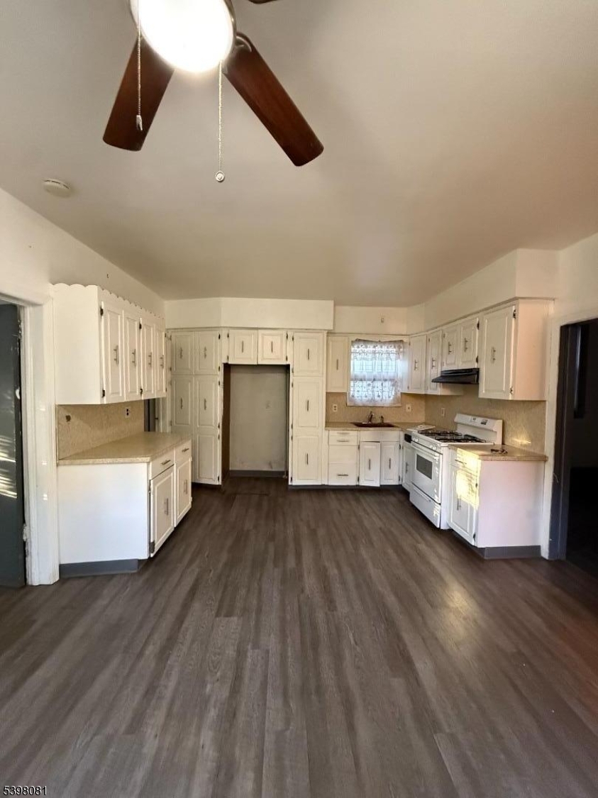 177 9th Street Passaic, NJ 07055 - Photo 1 of 6 a kitchen with stainless steel appliances kitchen island wooden floors granite counter tops and white cabinets