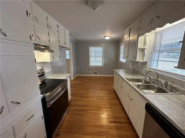 a kitchen with granite countertop stainless steel appliances a sink stove top oven and cabinets