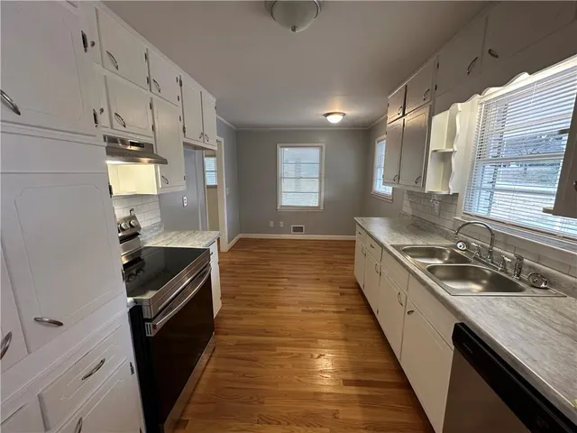 a kitchen with granite countertop stainless steel appliances a sink stove top oven and cabinets