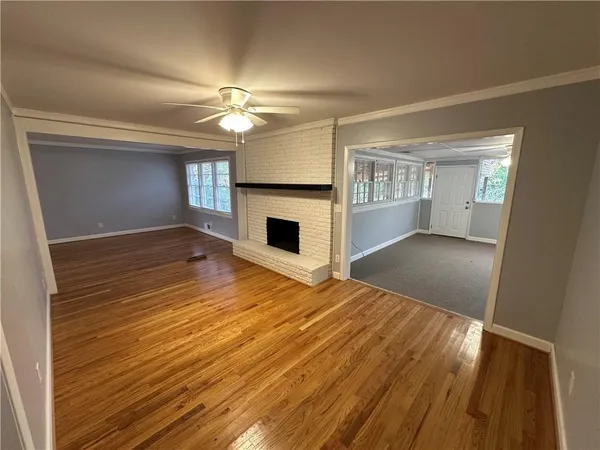 a view of a livingroom with a fireplace a ceiling fan and wooden floor
