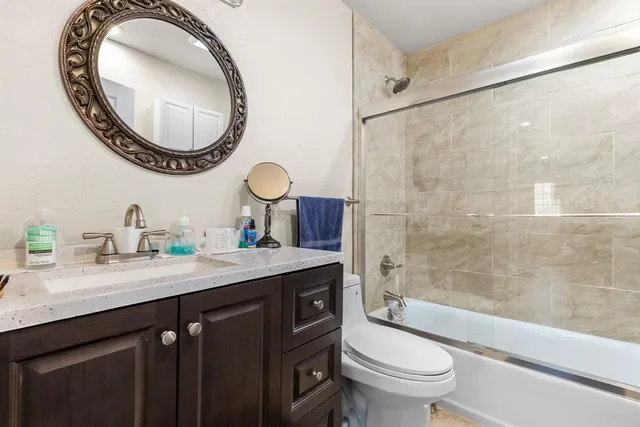 a bathroom with a granite countertop toilet sink and mirror