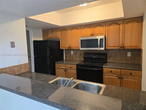 a kitchen with stainless steel appliances granite countertop a refrigerator and a stove top oven