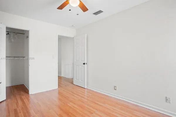 an empty room with wooden floor and a ceiling fan