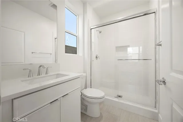 a bathroom with a shower sink vanity mirror and toilet