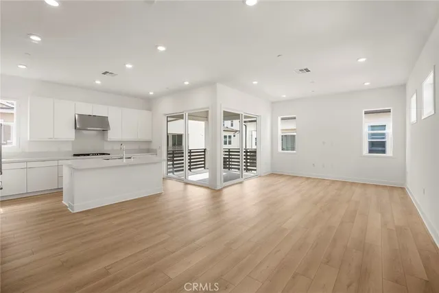 a large white kitchen with wooden floors and white walls