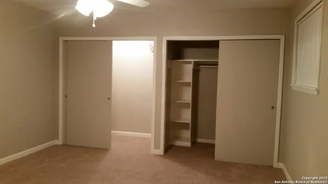 an empty room with closet and a chandelier fan