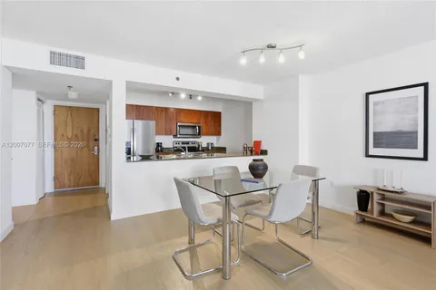 a kitchen with a dining table chairs and refrigerator