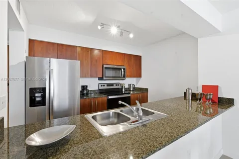 a kitchen with stainless steel appliances granite countertop a sink a refrigerator and a stove
