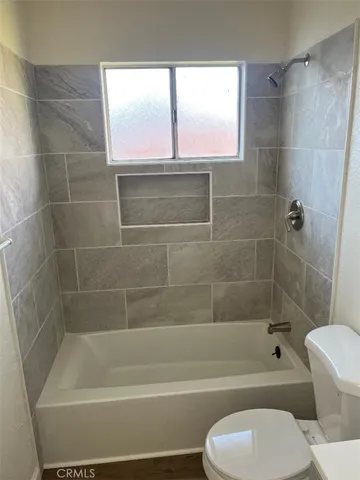 a bathroom with a white bath tub a toilet and a shower