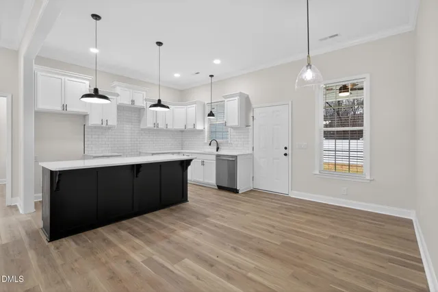 a large kitchen with a large counter top a sink stainless steel appliances and cabinets