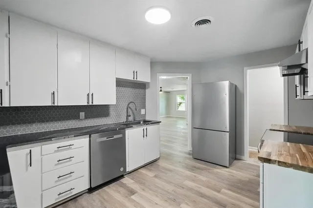 a kitchen with a refrigerator and white cabinets