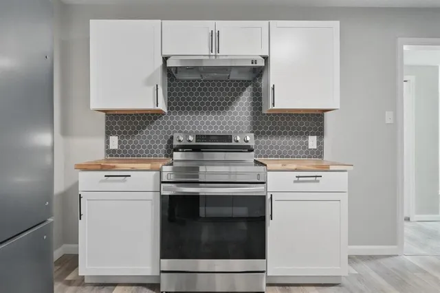 a kitchen with a stove and white cabinets