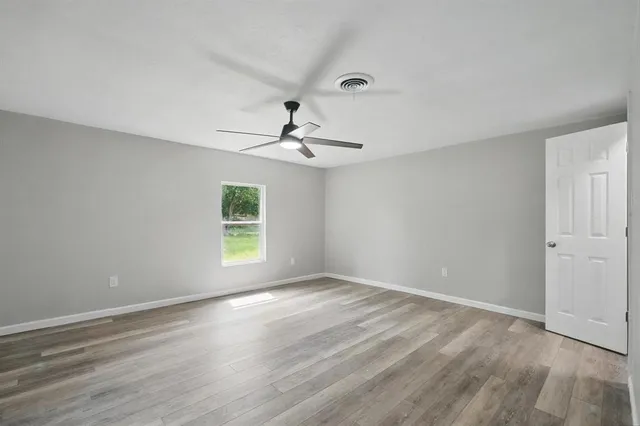 a view of empty room with wooden floor and fan