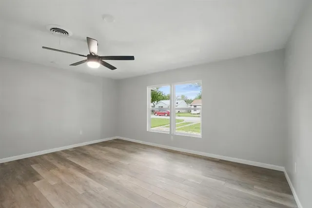 an empty room with window and ceiling fan