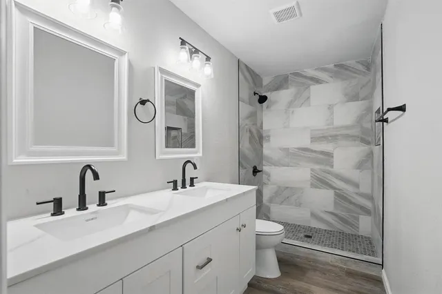 a bathroom with a double vanity sink toilet mirror and shower