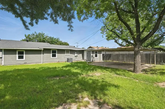 a view of a house with a yard deck and a large tree