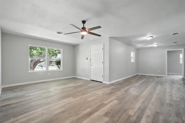 a view of an empty room with a window and wooden floor