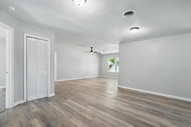 an empty room with wooden floor and windows