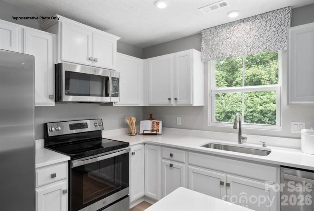 214 Maggys Way Pageland, SC 29728 - Photo 3 of 13 a kitchen with stainless steel appliances a sink a stove a microwave and cabinets