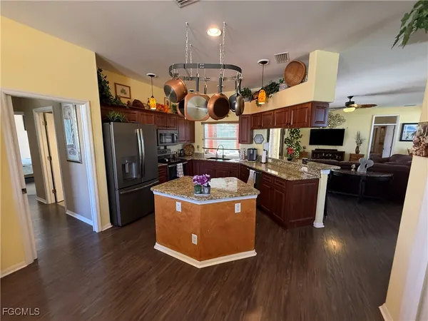 a living room with stainless steel appliances kitchen island granite countertop a stove and a refrigerator