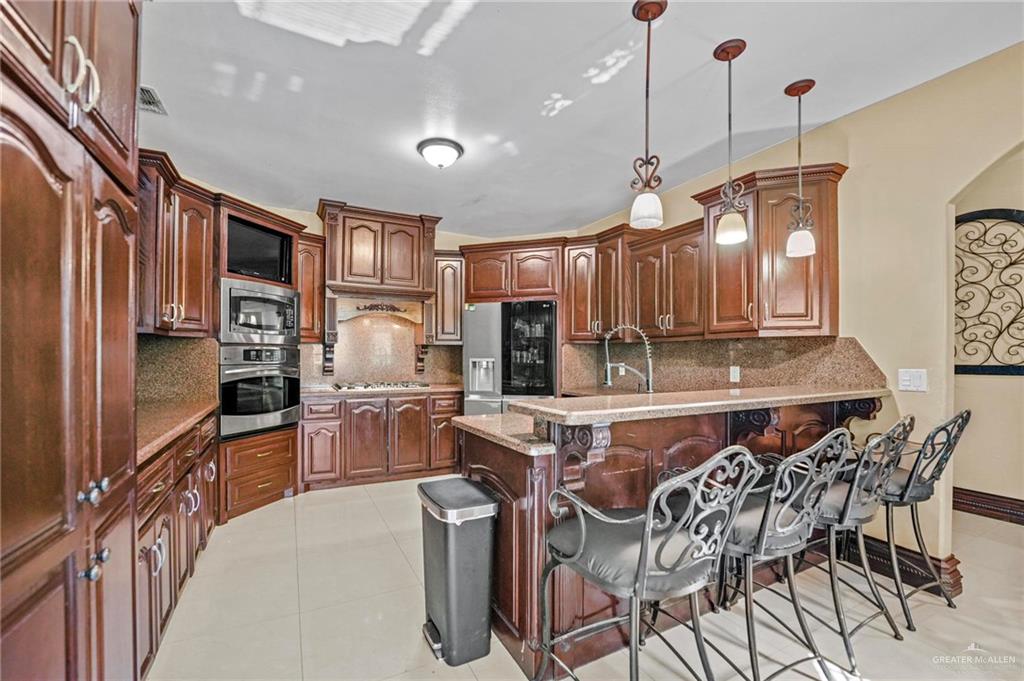 678 La Mesa Street Rio Grande City, TX 78582 - Photo 19 of 35 a kitchen with stainless steel appliances granite countertop a stove refrigerator and cabinets