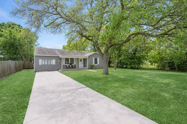 a front view of a house with a garden and trees