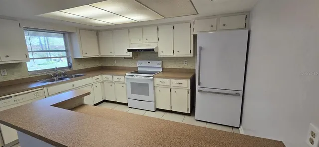 a kitchen with white cabinets and white appliances