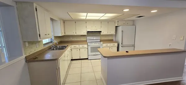 a kitchen with kitchen island granite countertop a sink a stove and refrigerator