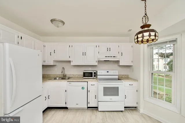 a kitchen with stainless steel appliances white cabinets and a window