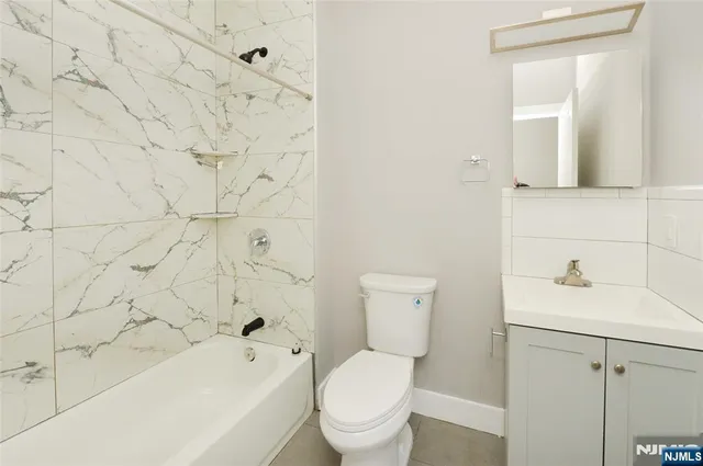 a bathroom with a toilet sink vanity tub and mirror