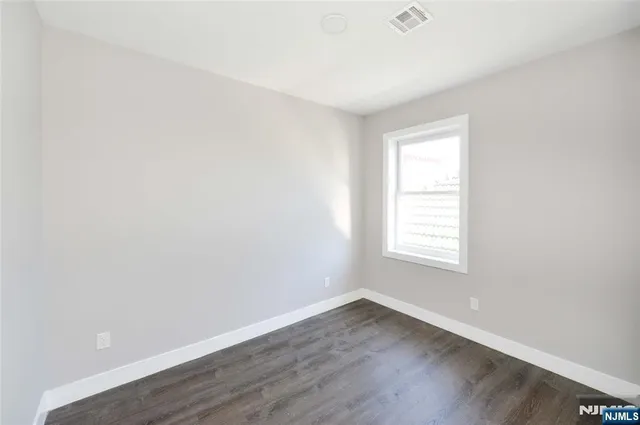 an empty room with wooden floor and window