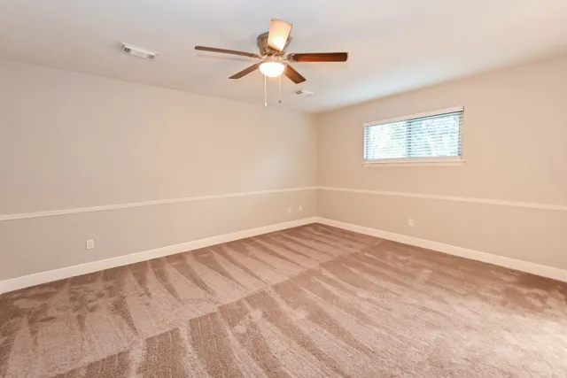 an empty room with a window and a ceiling fan
