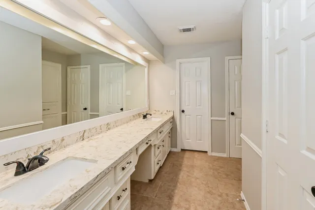 a spacious bathroom with a granite countertop double vanity sink and a mirror