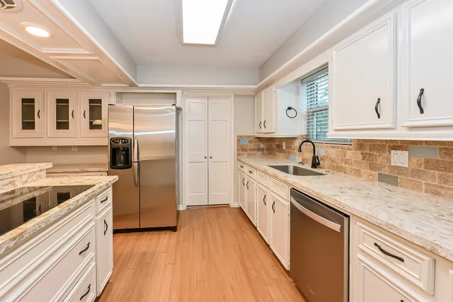 a kitchen with a sink cabinets stainless steel appliances and a window