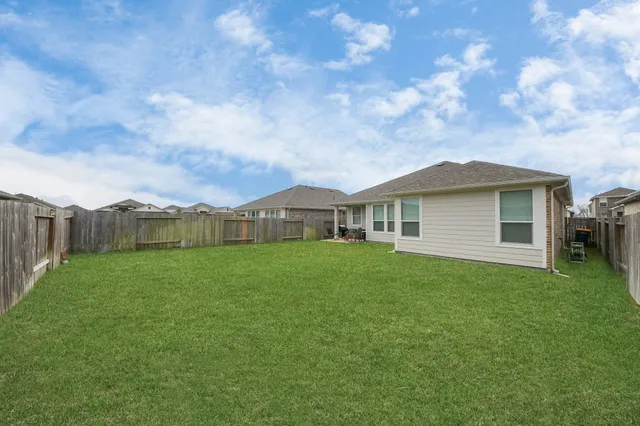 a view of a house next to a big yard and large trees