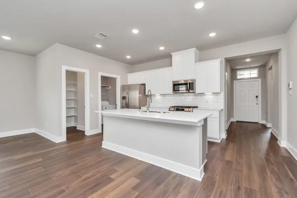 a kitchen with stainless steel appliances a sink stove and wooden floor