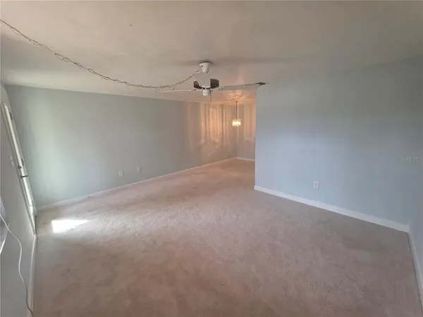 a view of a big room with windows and chandelier fan