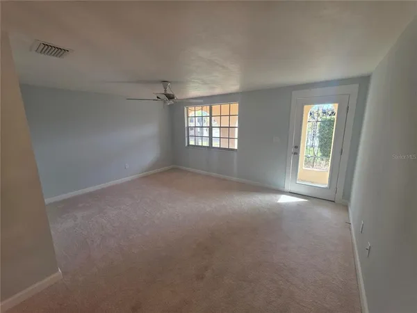 a view of a big room with windows and chandelier fan