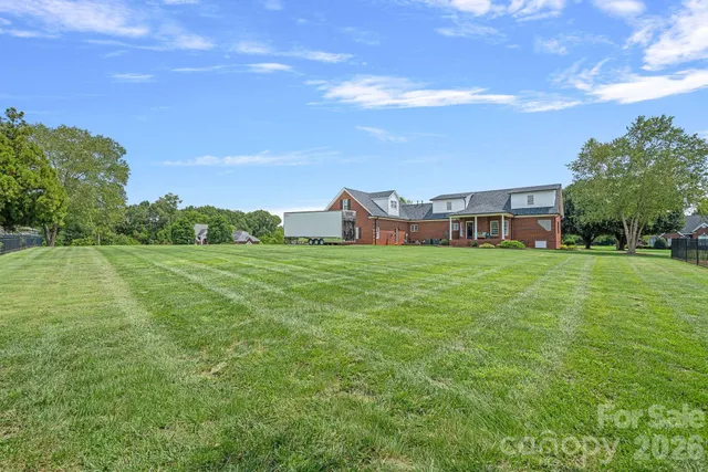 a view of a house with a big yard and large trees
