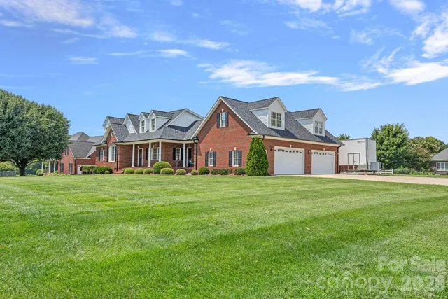 a view of a big house with a big yard and large trees