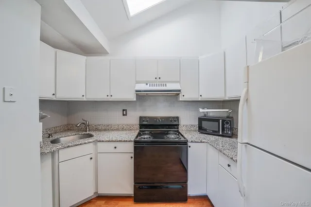 a kitchen with granite countertop white cabinets and stainless steel appliances