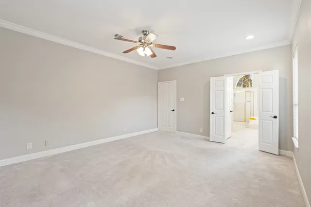 an empty room with chandelier fan and windows